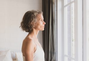Middle-aged woman looking out a window.