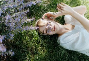 Woman laying on grass near flowers.