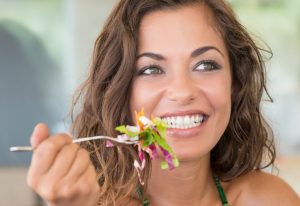 Mmiling woman eating salad.