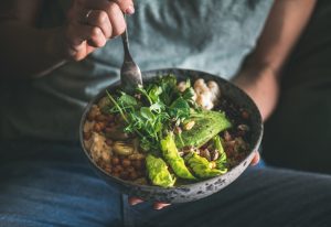 Person holding a plate of healthy food.