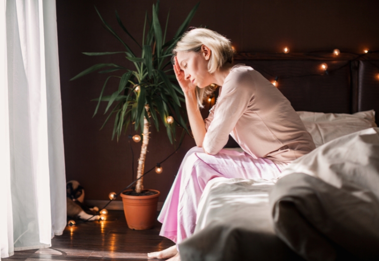 Concerned woman sitting on the edge of a bed.