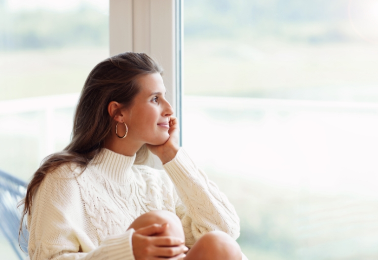 Woman looking out of a sunny window.