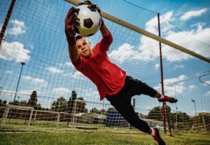 Teen boy catching a soccer ball.
