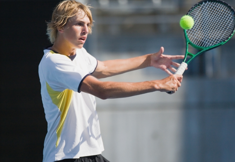 Teenage boy playing tennis.