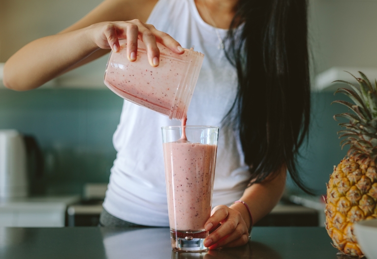 Woman pouring a smoothie into a glass.