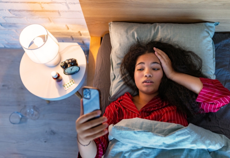 Woman in bed looking at phone.