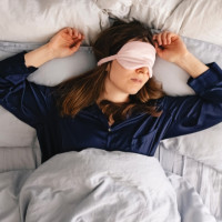 Woman sleepmaxxing with an eye mask.