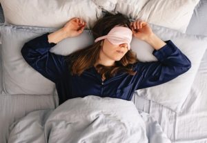 Woman sleepmaxxing with an eye mask.