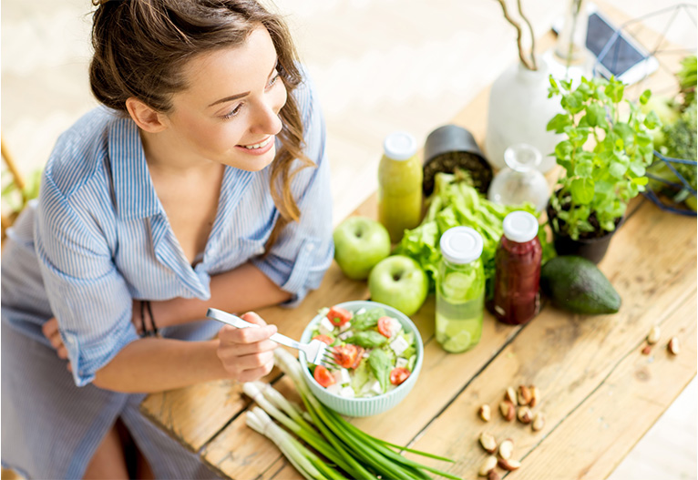 Woman eating salad at a table.