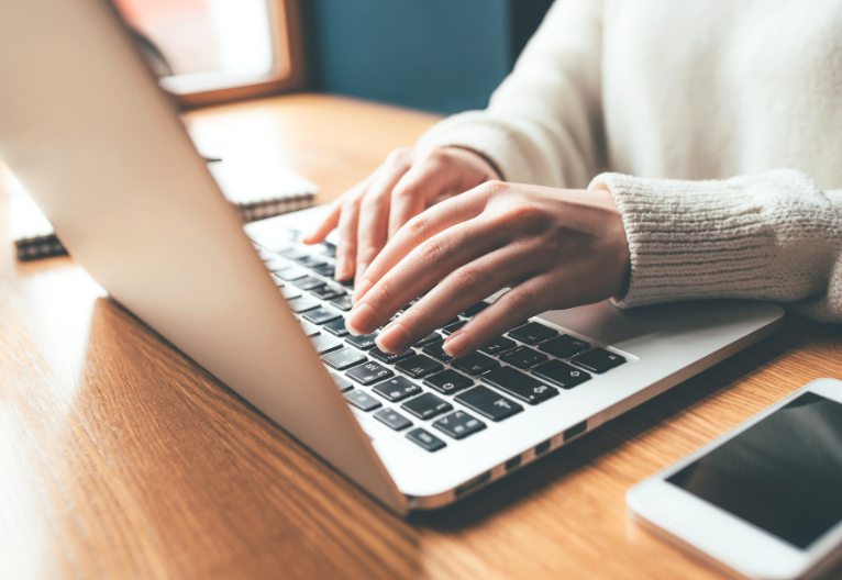 Woman typing on a laptop.