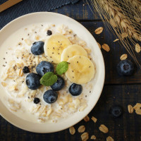 A bowl of porridge topped with blueberries and sliced banana.