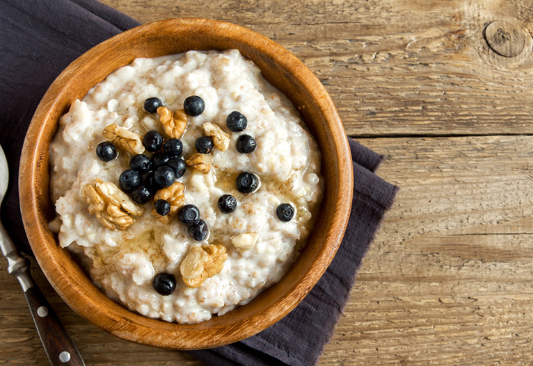 A bowl of porridge topped with berries and walnuts.