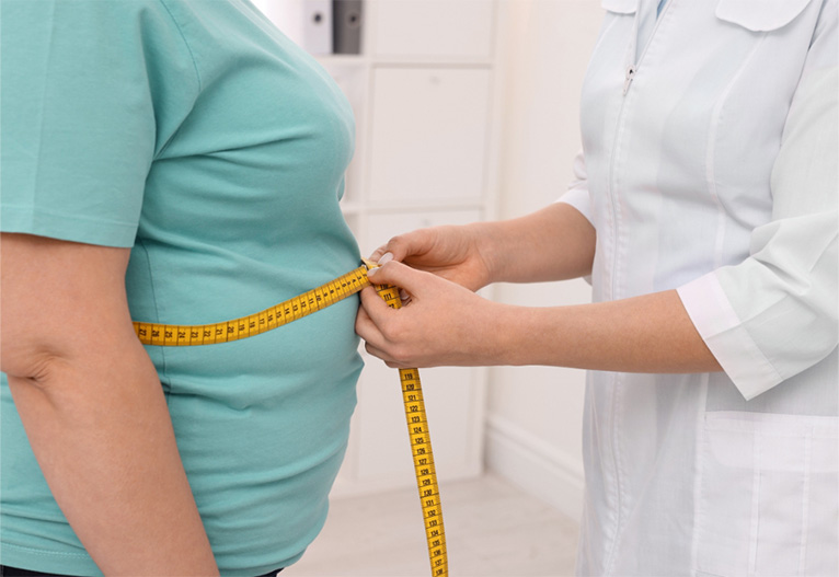 Overweight person having her waist measured by a health professional.