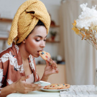 Woman eating a cookie while looking at her phone.