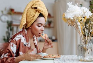 Woman eating a cookie while looking at her phone.