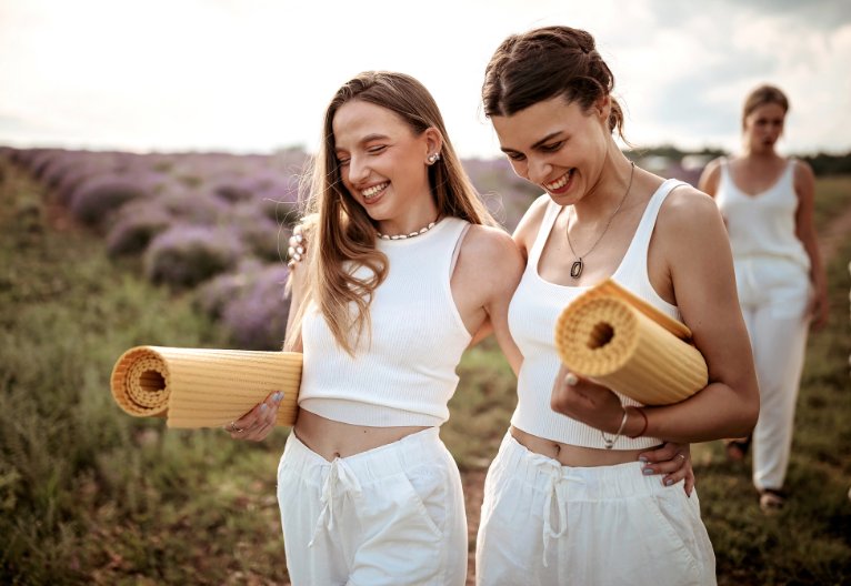 Girls in white walking with orange yoga mats.