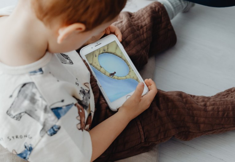 Young child slouching over a phone.