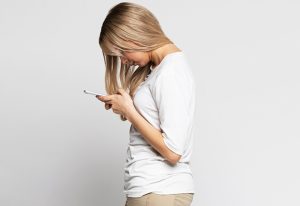 Woman slouching over her phone.