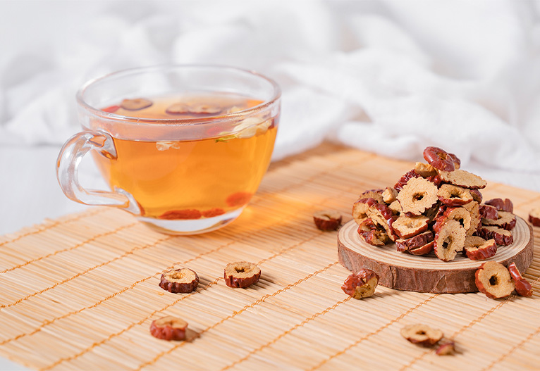 Chopped Chinese red dates next to a cup of tea.