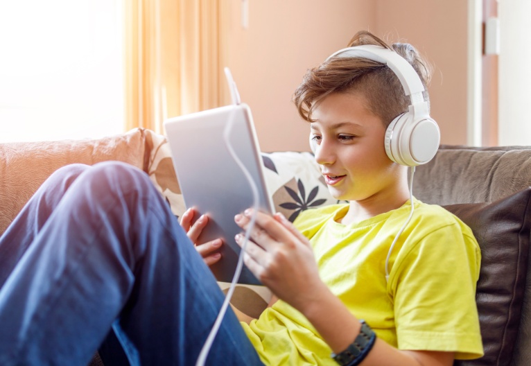 A boy on a sofa using his iPad.