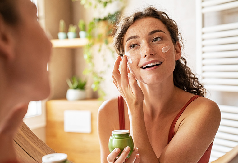 Woman applying moisturiser to her face.