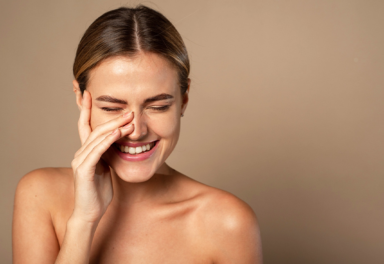 Smiling woman touching her face.
