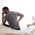 Man on bed with sore back.