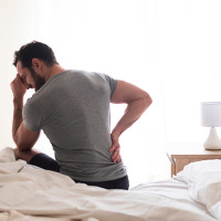 Man on bed with sore back.