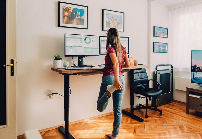 Woman stretching at a stand-up desk.