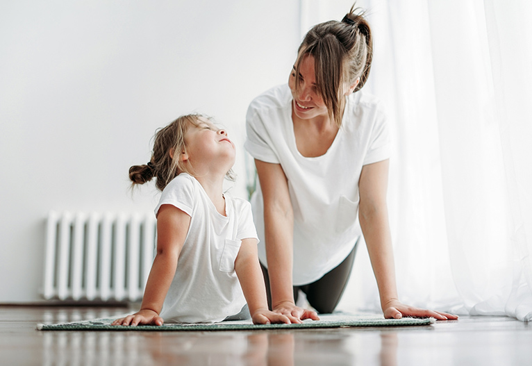 Woman doing yoga with her daughter.