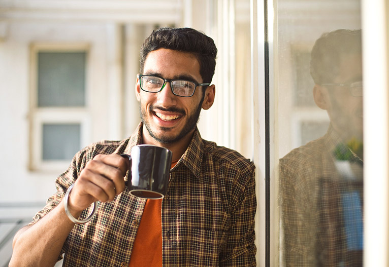 Man smiling with a mug of coffee.