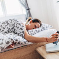 Woman waking up and looking at her phone.