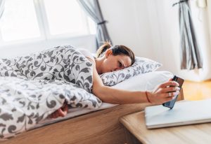 Woman waking up and looking at her phone.