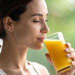 Woman sipping orange juice from a glass.