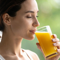 Woman sipping orange juice from a glass.
