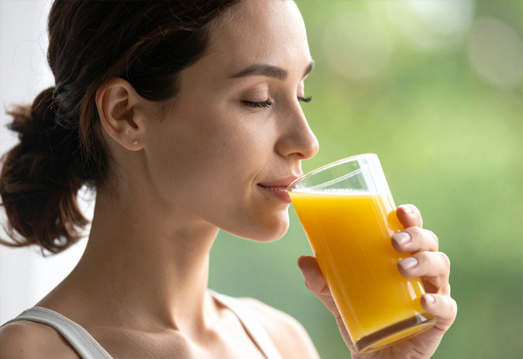 Woman sipping orange juice from a glass.