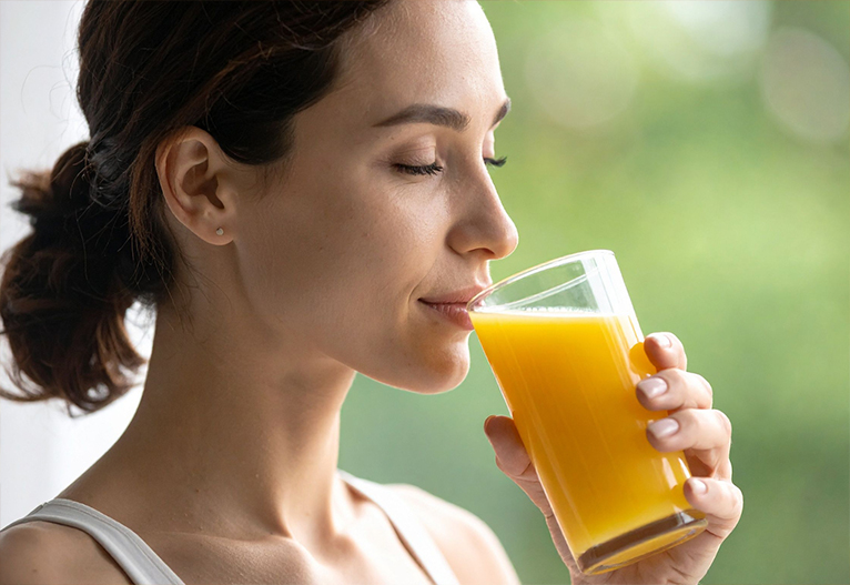 Woman sipping orange juice from a glass.