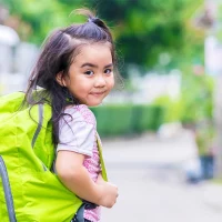 Girl walking to school with a green backpack.